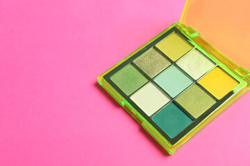 Colorful eyeshadow palette on pink background. Space for text
