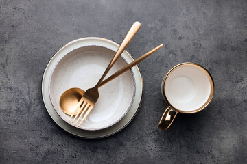 Stylish empty dishware and cutlery on grey table, flat lay