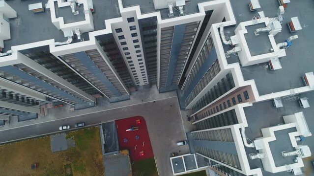 Highrise apartment buildings with yard near road junction with busy traffic in large town bird eye view. Urban landscape
