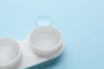 Case with contact lens on light blue background, closeup