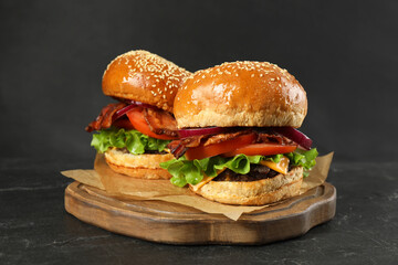 Tasty burgers on black wooden table. Fast food