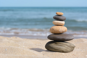 Obraz na płótnie Canvas Stack of stones on sandy beach near sea, space for text