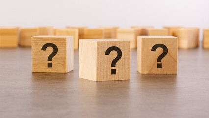 cube with question mark on wooden background. space for text