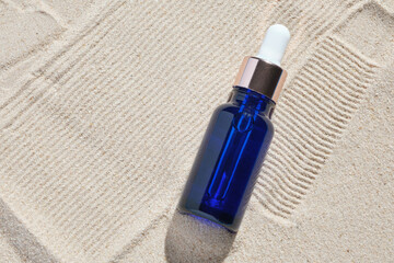 face serum of glass bottle with a pipette on a natural background with sand. Essential oil for moisturizing body skin. mockup of beauty fashion cosmetic bottle dropper product with skincare concept.