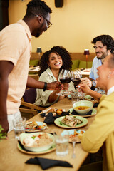 A small group of friends in a restaurant is toasting with red wine and having fun.