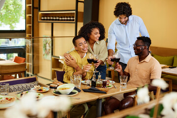 A small group of friends in a restaurant is toasting with red wine and having fun.