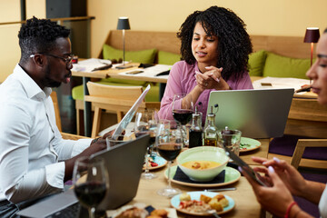 Fototapeta premium Businesspeople sit at the dinner table in a restaurant and brainstorm about a start-up project.