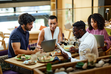 A multicultural busy businesspeople are working on a start-up project in a restaurant at the dinner table. - 517790984