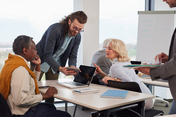 Fototapeta premium A group of senior students sit in a classroom with their teacher and work on a school project.