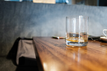 Empty liquor or whisky drinking glass on a wooden restaurant board table on an empty scene