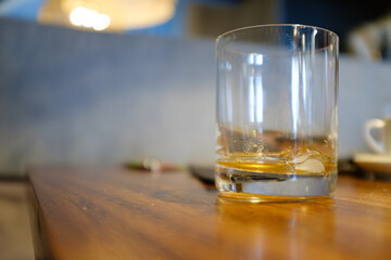 Empty liquor or whisky drinking glass on a wooden restaurant board table on an empty scene