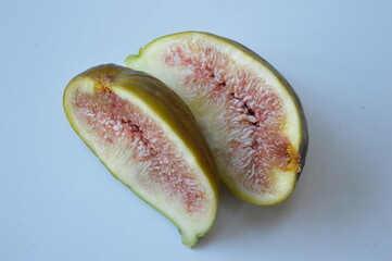 Two halves of huge green fig fruit on white background