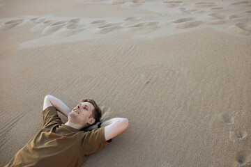 Young man laying in beach sand. People fatigue from sunburn and work. Summer sleeping and...
