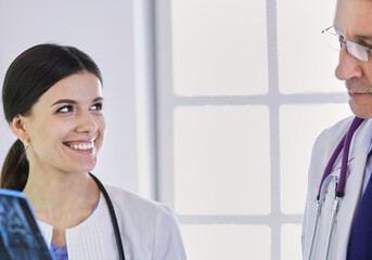Obraz premium Smiling doctors discussing patient's diagnosis looking at x-rays in a hospital