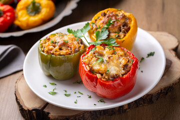 Stuffed peppers, halves of peppers stuffed with rice, dried tomatoes, herbs and cheese in a baking dish on a blue wooden table, top view. (Turkish name; biber dolmasi) - Powered by Adobe