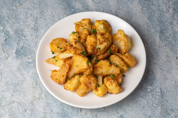 Fried in batter Cauliflower florets served on a black plate on a grey concrete table with ingredients, view from above, close-up, flatlay, copy space (Turkish name; karnabahar kizartmasi)