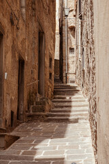 Bottom-up view to an ancient red brick arch with massive stone stairs leading to courtyard and blue sky in the background