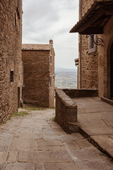 View to impressive ancient cobblestone street with ancient stone buildings and with blue sky and mountain landscape in the background