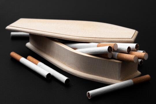 Moody image of real wood coffin filled with cigarettes in darkness concept for quit smoking to prevent death, lung cancer awareness and cigarettes kill