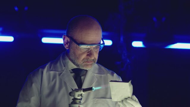 Professional tester testing , burning piece of fireproof building material  by gas torch inside  futuristic laboratory.  Construction engineer doing experiment . Physicist working in lab . Slow motion