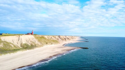 Panoramic aerial view of Bovbjerg Fyr lighthouse, cliffs and North Sea in summer with blue sky on one side and dark gathering clouds on the other side, Jutland, Denmark