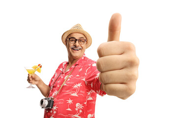 Happy mature male tourist holding a cocktail and showing thumbs up
