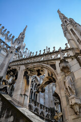 Gothic spires and white marble statues on Cathedral of Milan Duomo di Milano rooftop. Largest church in Italy and popular tourist attraction