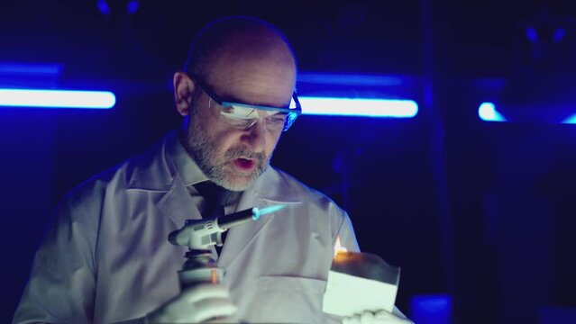 Professional tester testing , burning piece of fireproof building material by gas torch inside futuristic laboratory. Construction engineer doing experiment . Physicist working in lab . Slow motion