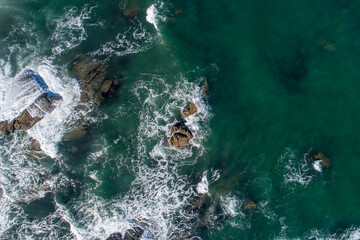 Aerial overhead drone view of waves on the rocks of the shore