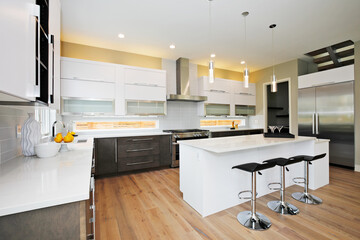 Luxury kitchen in a brand new home with white cabinets and wooden brown doors and beige walls. 