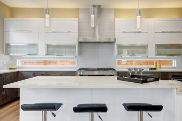 Luxury kitchen in a brand new home with white cabinets and wooden brown doors and beige walls. 
