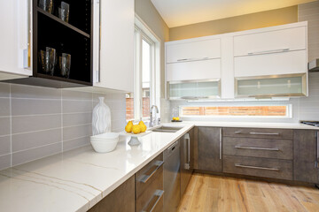 Fototapeta na wymiar Luxury kitchen in a brand new home with white cabinets and wooden brown doors and beige walls. 