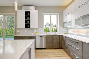 Luxury kitchen in a brand new home with white cabinets and wooden brown doors and beige walls. 