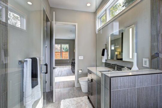 Contemporary bathroom interior with walking shower with grey tiles and large glass door. Luxury new home. 