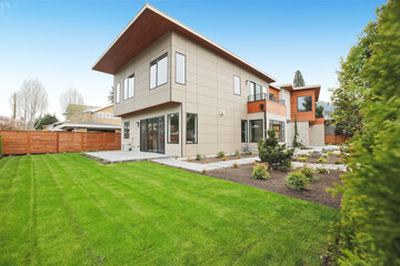 Contemporary style home luxury home exterior with brown walls and dark framed metal windows. Green Northwest landscaping. 
