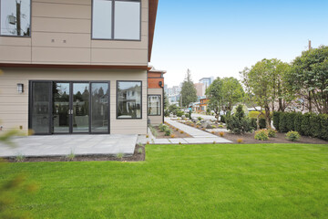 Contemporary style home luxury home exterior with brown walls and dark framed metal windows. Green Northwest landscaping. 