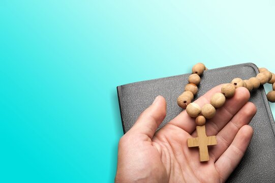 Human hand holding wooden cross crucifix. Catholicism, Christianity, Thanksgiving, Catholic and Christian faith concept.