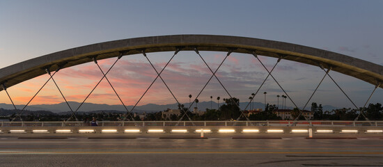 Palm trees silhouetted against a beautiful sunset viewed through the 6th street bridge in Los...