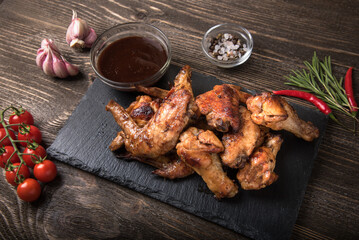 Barbecue chicken wings on a stone board on a wooden table