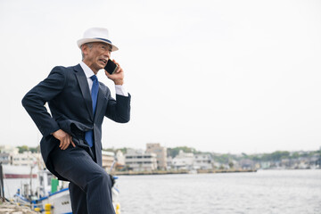 日本人　ビジネス　港　漁港　仕入れ　海　スーツ姿の中年男性