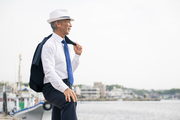 日本人　ビジネス　港　漁港　仕入れ　海　スーツ姿の中年男性