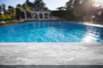 Empty table top and blurred swimming pool in tropical resort in summer for display or montage your products.