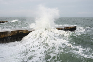 storm on the beach the waves crash on the pier