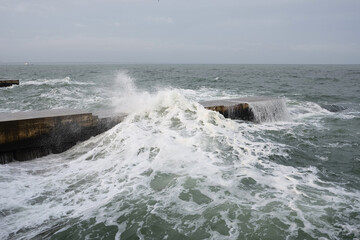 storm on the beach the waves crash on the pier