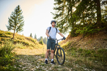 Fototapeta premium A cyclist rides a bike next to him through the forest roads