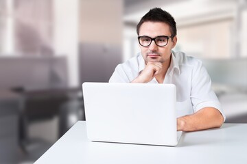 Young businessman using computer in office, thinking. Happy middle aged man, entrepreneur working online.