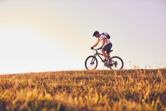 A cyclist rides a bike on forest roads at sunset