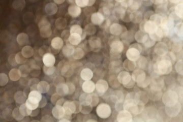 Golden and beige bokeh on a black background.Wallpaper Festive phone.Festive Background.Christmas background. Glowing bokeh. Shining bokeh background.Beautiful bokeh in gold colors.