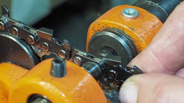 Macro closeup of operator using special riveting machine to fix chainsaw chain