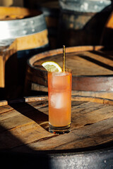 pink lemonade cocktail drink in sun on whiskey barrel with golden drinking straw